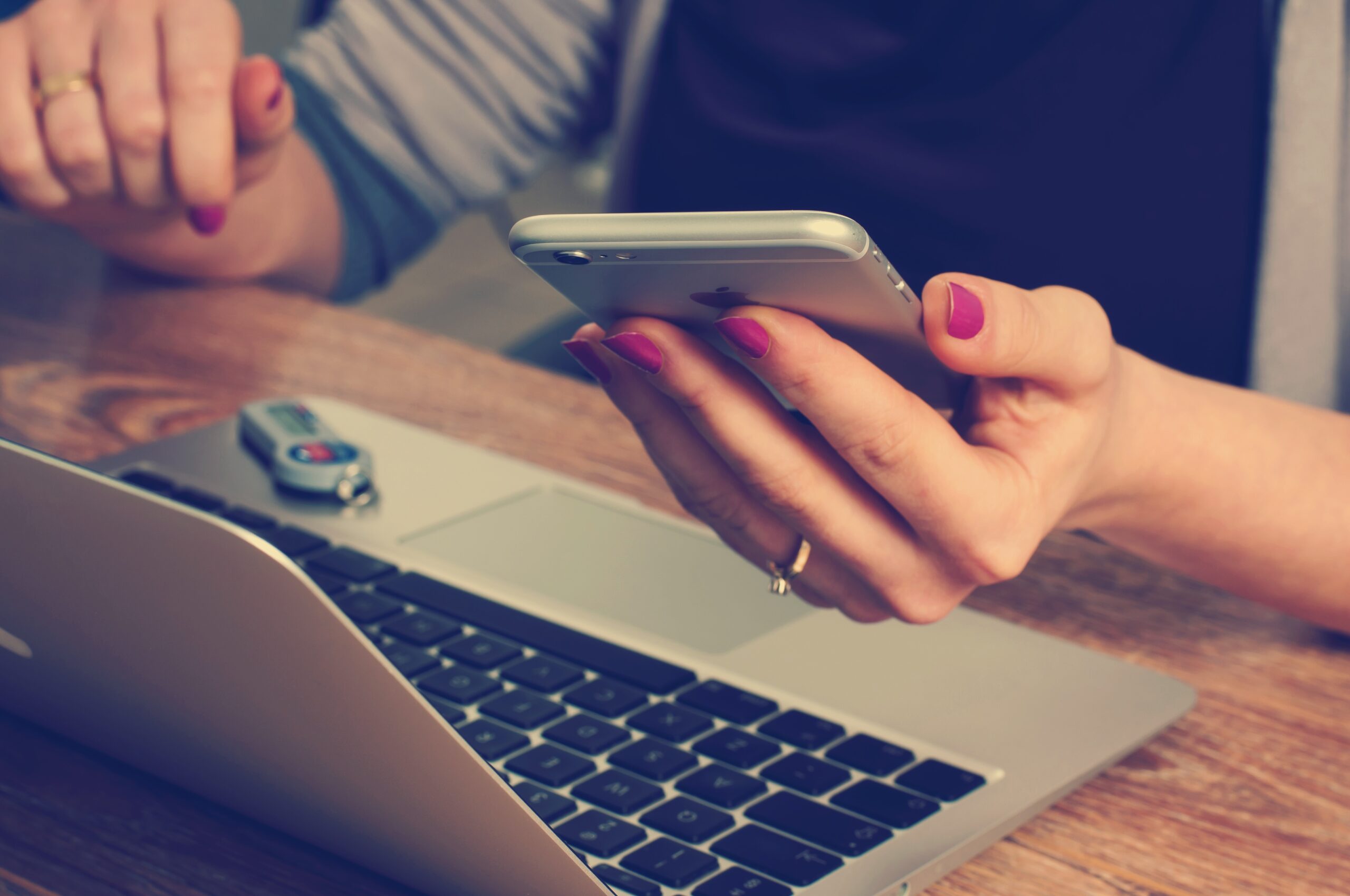 Person sidder med en smartphone og laptop